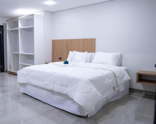 a bedroom with a large white bed with a wooden headboard at Il Divo Boutique Hotel in Ciudad del Este