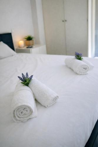 two rolled towels on a white bed with purple flowers at Corinth Central Studio in Korinthos