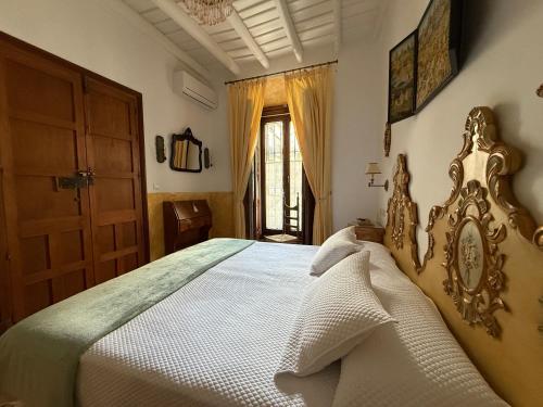 a bedroom with a large white bed with a wooden headboard at Benafique La casa del Ciprés - refugio de calma en la Sierra de Huelva in Cortegana