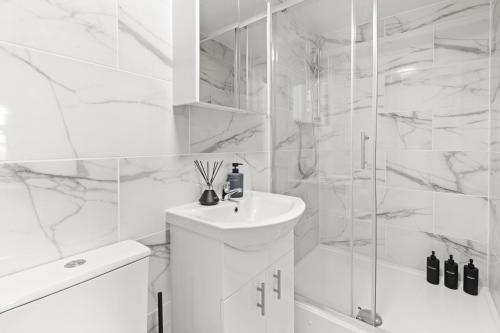 a white bathroom with a sink and a shower at Cheshire Gold- studio apartment, Warrington in Warrington