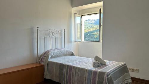 a bed in a white room with a window at Balcón de Mágina in Torres