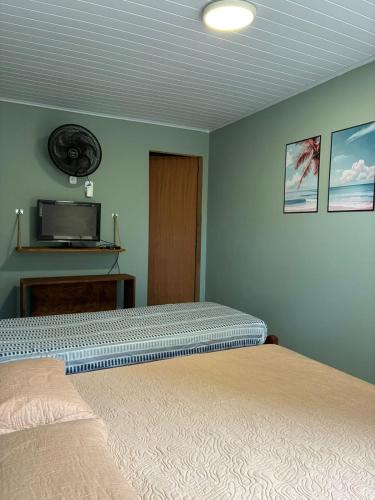 a bedroom with a bed and a tv on the wall at Sol e Sal Suítes Aconchegantes in Saquarema
