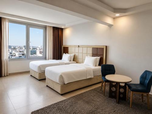 two beds in a hotel room with a table and chairs at Diamond Star Hotel فندق النجمة الماسية in Seeb