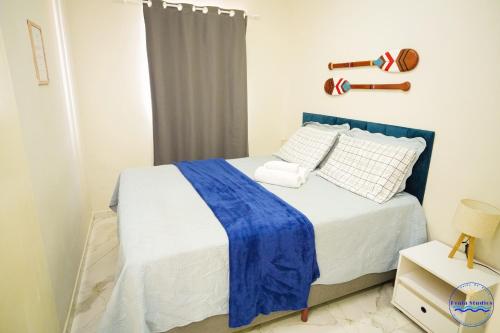a bedroom with a bed with a blue blanket on it at Praia Studios in Vila Velha
