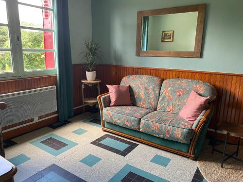 a living room with a couch and a mirror at Maison Le Merle Rouge in Sazeray
