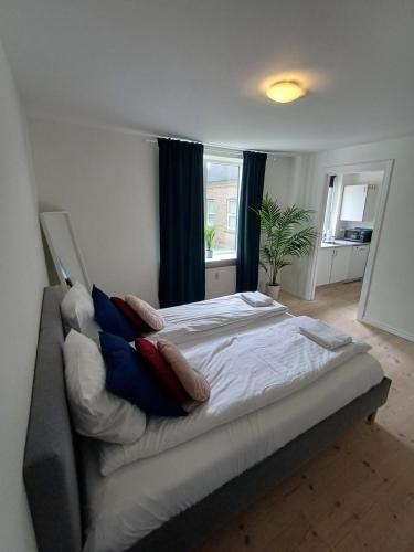 a large bed with pillows on it in a bedroom at Charming 2 bedroom apartment free parking in Hjørring