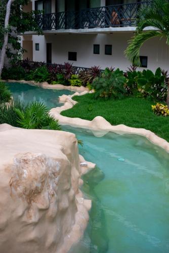 a swimming pool with a rock in a yard at Spacious Loft with Balcony Near Hotel Zone Palais Tulum by Waves in Tulum