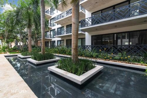 a building with palm trees and a swimming pool at Spacious Loft with Balcony Near Hotel Zone Palais Tulum by Waves in Tulum