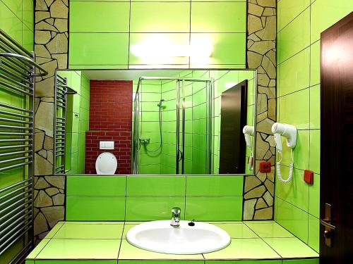 a green bathroom with a sink and a mirror at Hotel Vinopa in Hustopeče