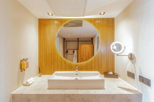 a bathroom with a sink and a round mirror at Santo Domingo Bay Convention Resort & Casino in Boca Chica