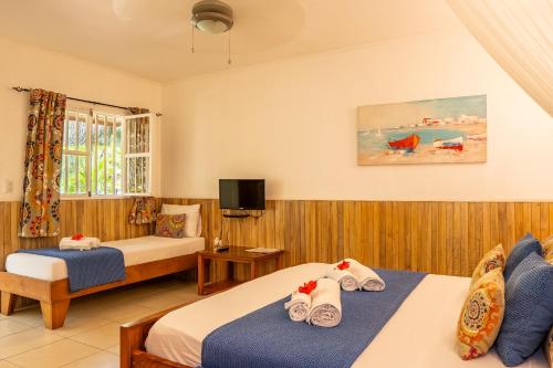 a hotel room with two beds and a tv at Casa Mapache Pool and Breakfast Available near Tamarindo Beach in Tamarindo