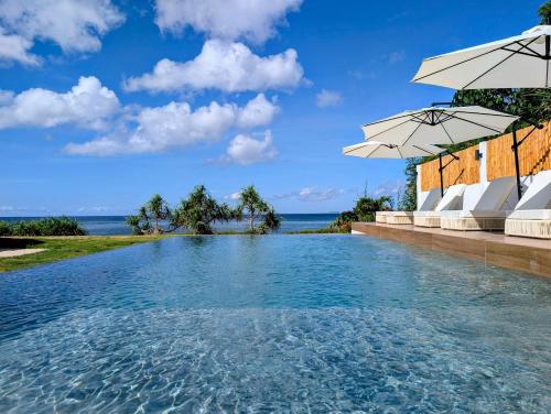 a swimming pool with umbrellas and the ocean at Villa Nindot - Private pool villas - Adults only in Siquijor