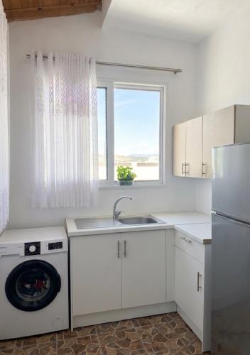 a white kitchen with a sink and a dishwasher at Villa Murataj in Ksamil
