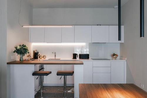 a kitchen with white cabinets and a counter with stools at La Terrazza - Private Jacuzzi in Downtown Como in Como