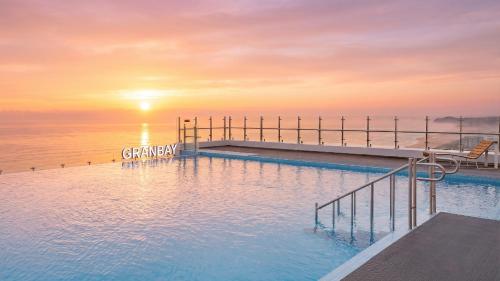 a swimming pool with the sun setting over the ocean at Urbanstay Naksan Beach in Yangyang