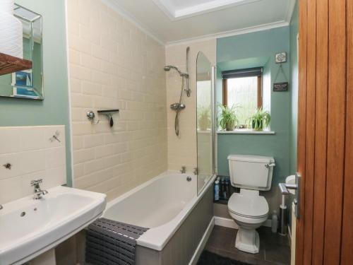 a bathroom with a tub and a toilet and a sink at Puidrac Cottage in Lochearnhead