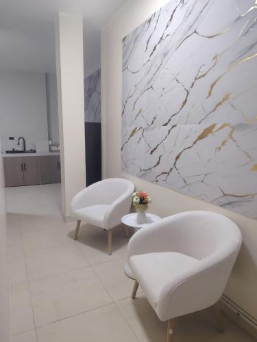 a bathroom with two white chairs and a marble wall at Minidepartamento Independiente in San José de Chaltura