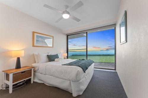 a bedroom with a bed and a large window at Harbourside Unit 2 7 Soldiers Point Road in Soldiers Point