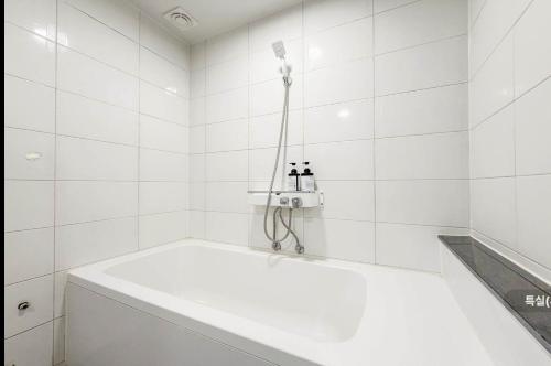 a white bath tub in a white tiled bathroom at Hole in One Hotel in Chuncheon