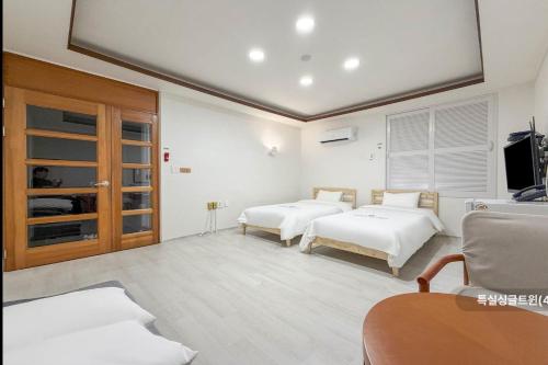 a white room with two beds and a tv at Hole in One Hotel in Chuncheon
