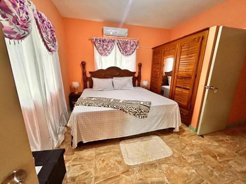a bedroom with a bed with orange walls and a refrigerator at Mammee Bay Hideaway in Ocho Rios