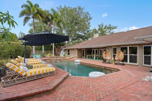 a swimming pool with lounge chairs and an umbrella at SolMaré - 5BR, Pool, Spa, Mini-Golf, Outdoor Kitchen, Fire Pit, Game Room in Bradenton