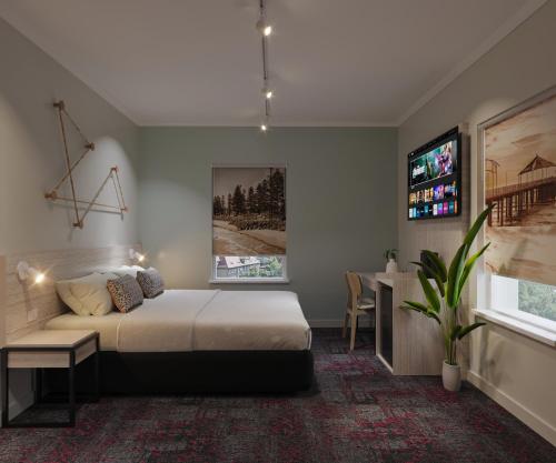 a bedroom with a bed and a desk and a tv at Nightcap at Esplanade Hotel in Brighton