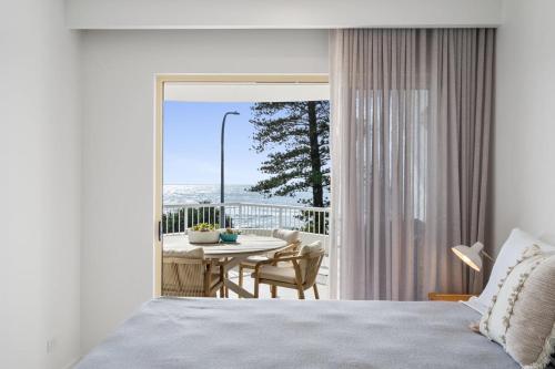 a bedroom with a bed and a balcony with a table at 6 Baywatch Apartments in Coolum Beach