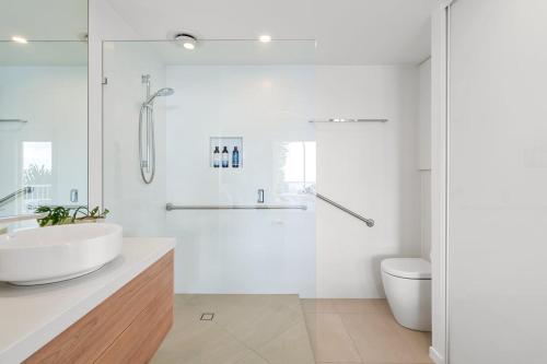 a white bathroom with a shower and a sink at 6 Baywatch Apartments in Coolum Beach