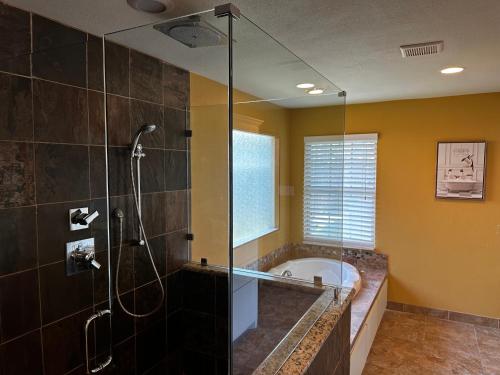 a bathroom with a tub and a glass shower at Madeira Suite in Fort Worth