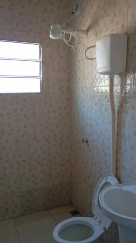 a bathroom with a toilet and a sink and a window at Chácara do tio Tuta in Araçariguama