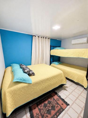 two beds in a room with yellow and blue at inn house almendros in San Andrés
