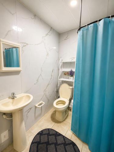 a bathroom with a blue shower curtain and a toilet at inn house almendros in San Andrés