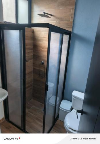 a bathroom with a toilet and a glass shower at Loft Privado Seguridad 24HRS a 15 de piramide de cholula in Cholula