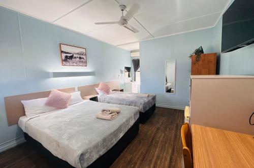 two beds in a room with blue walls at Charters Towers Motel in Charters Towers