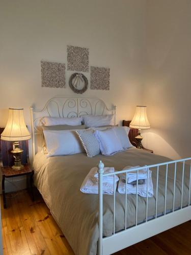 a bedroom with a white bed with two lamps at Riverstone Cottage at Murray Bridge in Murray Bridge