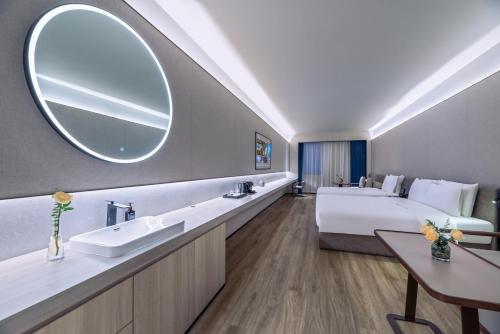 a hotel room with a bed and a sink and a mirror at Crystal Orange Hotel Suzhou Xiangcheng in Suzhou