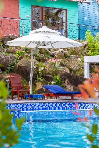 an umbrella and two chairs next to a swimming pool at Solivo Ecolodge Phu Quoc in Phú Quốc