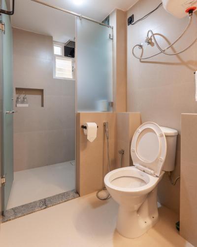 a bathroom with a toilet and a glass shower at Encontro Homestays in Dona Paula
