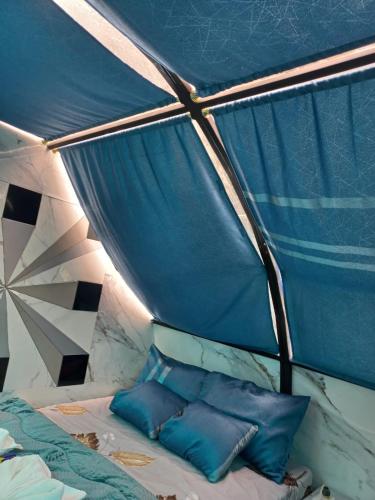 a bed in a tent with blue pillows on it at Glamping La Escapadita in Baños