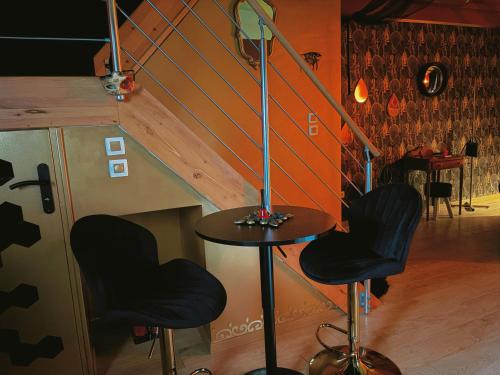 a table and two stools in a room with a staircase at Maison love rooms in Tours