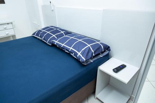 a bed with a pillow and a remote control on it at Loft Completo com Smart TV e Frigobar Compacto 08 in Presidente Prudente