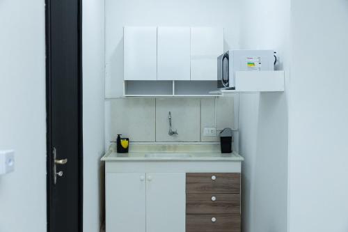 a white kitchen with a sink and a microwave at Loft Completo com Smart TV e Frigobar Compacto 08 in Presidente Prudente