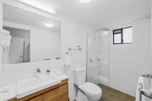 a white bathroom with a toilet and a shower at Beach Days, Ocean Rooftop & Spa - Sleeps 8 in Marcoola