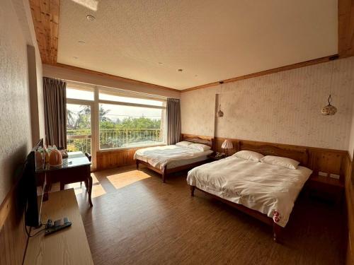 a bedroom with two beds and a television and a window at 玉灣鵬灣民宿Jade Bay B&B in Donggang