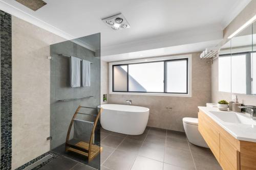 a bathroom with a tub and a toilet and a sink at Glassy Waters in Sussex Inlet