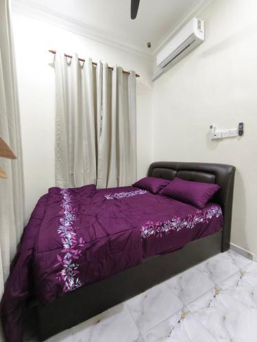 a bed with a purple comforter in a room at Asyhani Cottage in Bachok