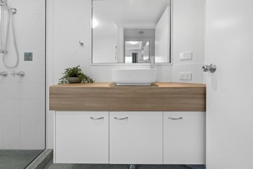 a white bathroom with a sink and a mirror at Mackay Seabreeze Apartments in Mackay