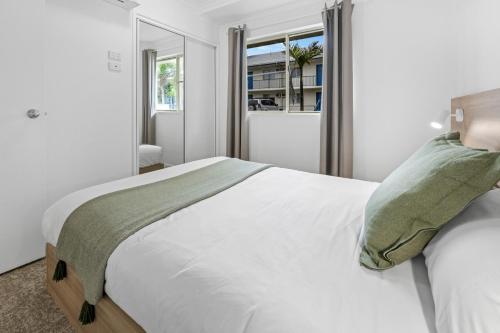 a bedroom with a large white bed with a window at Mackay Seabreeze Apartments in Mackay