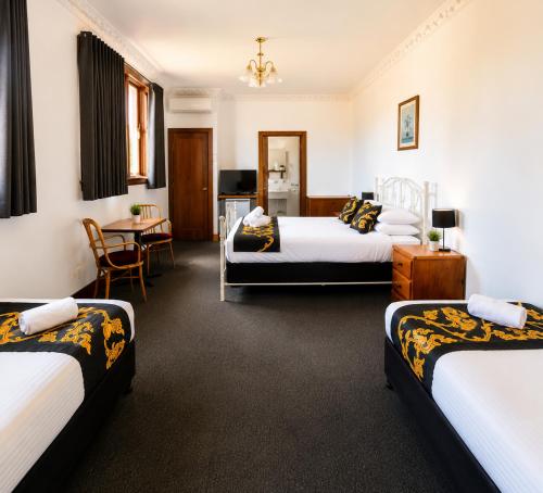 a hotel room with two beds and a table at Golden Age Hotel in Omeo